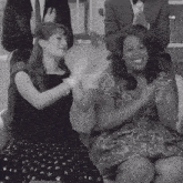 two women are clapping while sitting next to each other in a black and white photo