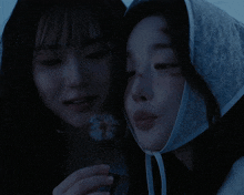 a woman in a white hat holds a dandelion next to another woman in a blue hat