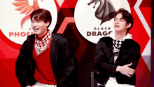 two men are standing in front of a black drago sign