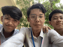 three young men are posing for a picture and one has a lanyard around his neck