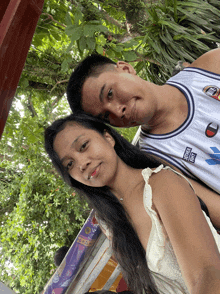 a man and a woman are posing for a picture while the man is wearing a jersey that says just do it
