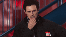a man in a black jacket has a name tag that says alpha