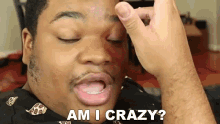 a man is holding his hand to his forehead and says am i crazy .
