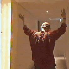 a man is standing in a hallway with his arms outstretched and a hat on .