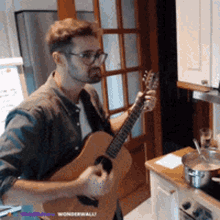 a man is playing a guitar in a kitchen with the words wonderwall on the bottom right