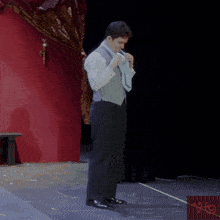 a man in a suit is standing on a stage in front of a red curtain with a sticker that says vto
