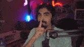 a man wearing headphones holds his finger to his mouth in front of a microphone