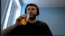 a man wearing headphones and a microphone is drinking from a glass .