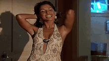 a woman in a white and gold dress is standing with her arms outstretched and smiling .