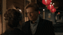 two men are hugging and kissing in front of lanterns