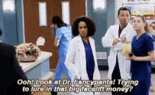 a group of doctors and nurses are standing in a room and one of them is talking to another doctor .