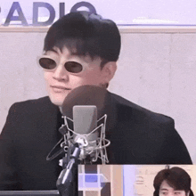 a man wearing sunglasses is sitting in front of a microphone