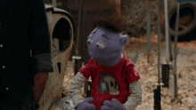 a purple puppet wearing a red shirt with the number 60 on it