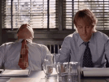two men are sitting at a table with their heads down