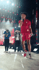a man in a red shirt with the number 7 on it stands on a stage