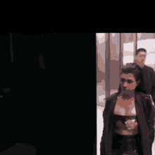 a woman with long hair is standing in a dark room with a man standing behind her .
