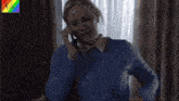 a woman in a blue shirt is talking on a phone