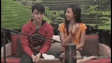 a boy and a girl are sitting on a couch in front of a microphone .