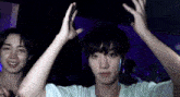 two young men are dancing in a dark room with their arms in the air .