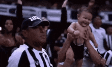 a referee is holding a baby in his arms in a crowd .