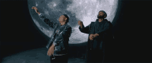 two men are dancing in front of a large full moon