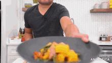 a man in a black shirt is reaching for a plate of food with the words made in animatica below him