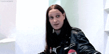a man with long hair is wearing a black leather jacket