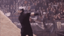 a man is doing a trick in front of a crowd while wearing a helmet .