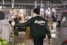 a man wearing a black good vibes jacket is walking through a market