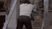 a man is walking down a set of stairs while holding a ladder .