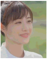 a close up of a woman 's face with a ponytail and a smile .