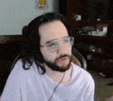 a man with glasses and headphones is sitting in a chair .