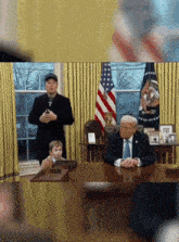 a man in a suit and tie sits at a desk while a little boy looks on