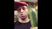 a man in a red hat is holding a green object