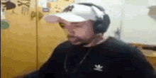 a man wearing headphones and a baseball cap is sitting at a table .