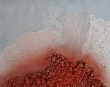 a pile of red rocks sits on top of a pile of white paint