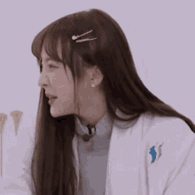 a woman with long hair is wearing a white coat and a microphone in her mouth .