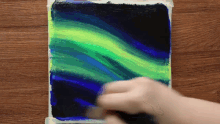 a person is painting the aurora borealis on a wooden table