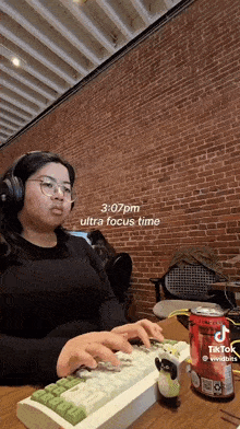 a woman wearing headphones is typing on a keyboard with a can of soda next to her