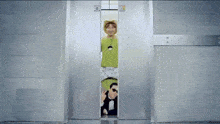 a man in a tuxedo and a woman in a green shirt are standing in an elevator