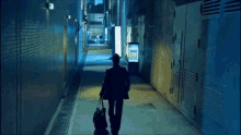 a man with a suitcase walks down an alleyway at night