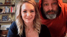 a man in a red hoodie stands next to a woman in a black top