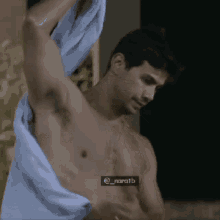 a shirtless man wrapped in a blue towel is standing next to a pool .