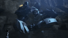 a man standing next to a large robot in a dark cave