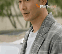 a man wearing a plaid jacket and a white t-shirt with a tv logo on the bottom