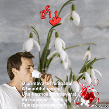 a man drinking a cup of coffee in front of snowdrop flowers with a picmix watermark