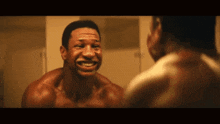 a shirtless man is smiling at himself in a mirror