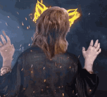 a woman in a black and gold dress is surrounded by fire