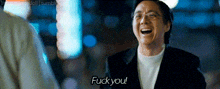 a man with glasses is laughing and saying fuck you .