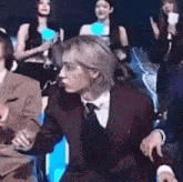 a man in a suit and tie is sitting in a chair in front of a crowd .